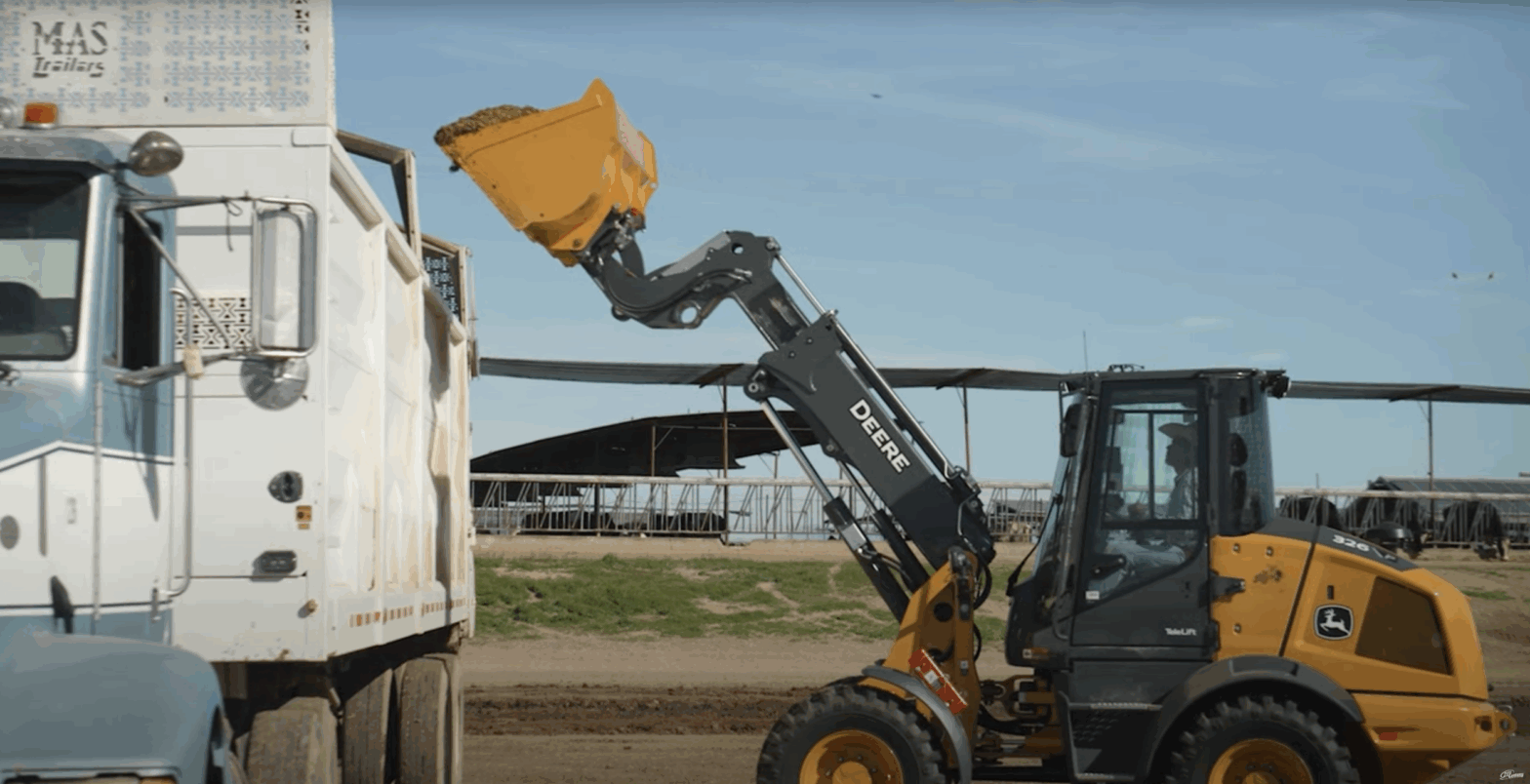 326P Telescoping Loader dumping dirt into a truck.